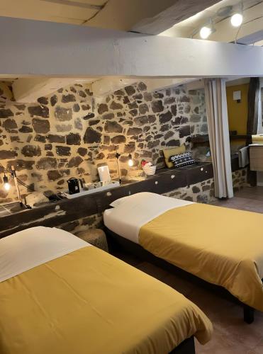 two beds in a room with a stone wall at Chambres D'hôtes du Pentadou in Felzins
