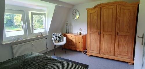 a bedroom with a wooden cabinet and a dresser with a mirror at Fewo D und R Schwesternherz in Naumburg