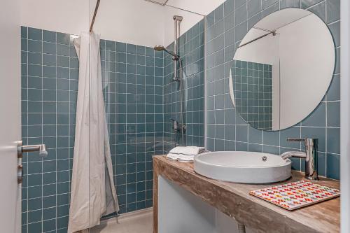a blue tiled bathroom with a sink and a mirror at Calçada in Alcácer do Sal