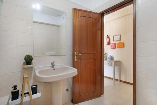 a bathroom with a sink and a wooden door at T0 Grota in Buarcos