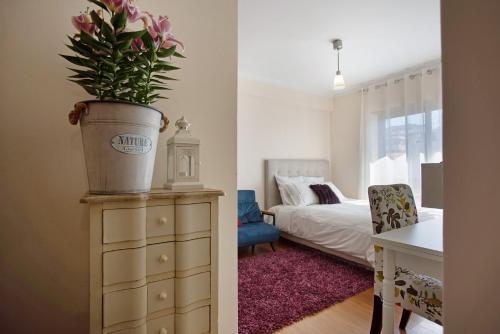 a bedroom with a potted plant on top of a dresser at T0 Grota in Buarcos
