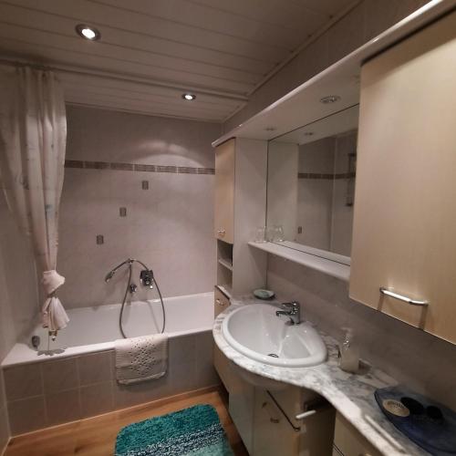 a bathroom with a sink and a tub and a mirror at Ferienwohnung Hörnleblick in Burgberg