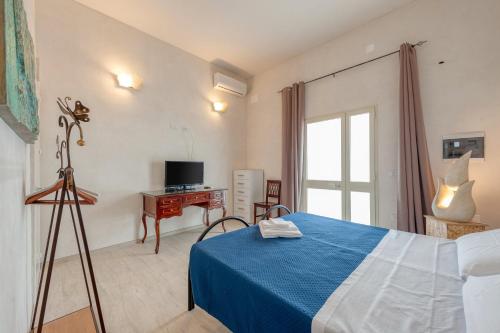 a bedroom with a bed and a desk with a television at Anghelos in Lizzanello