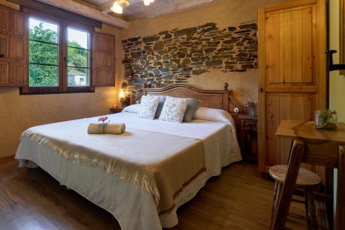 a bedroom with a large bed with a stone wall at El Pajariel ll in Valdecañada