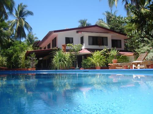 a house with a swimming pool in front of a house at Beso del Viento (Adults Only) in Parrita