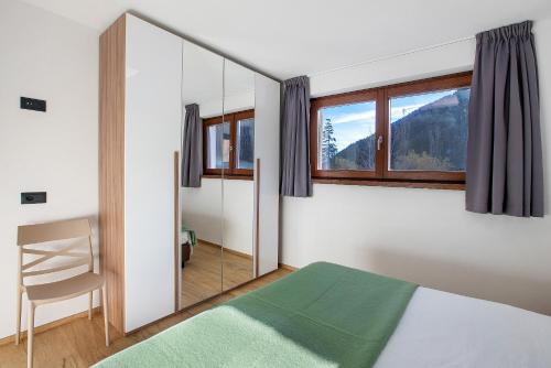 a bedroom with a mirror and a bed and a chair at Chalet Serenella in Valdidentro