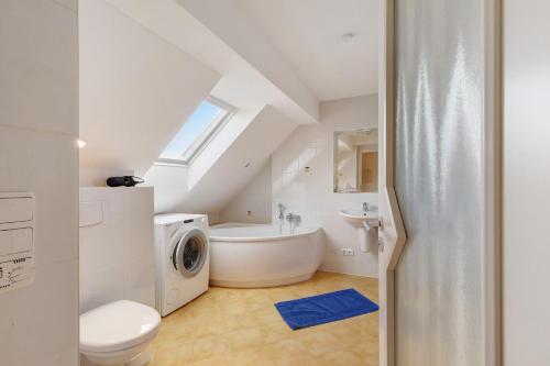 a bathroom with a tub and a sink and a washing machine at Birkethof Romantik-Appartement in Mickhausen