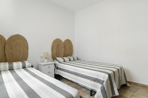 two beds in a room with white walls at Apartamento Perez Zara 3 in Conil de la Frontera