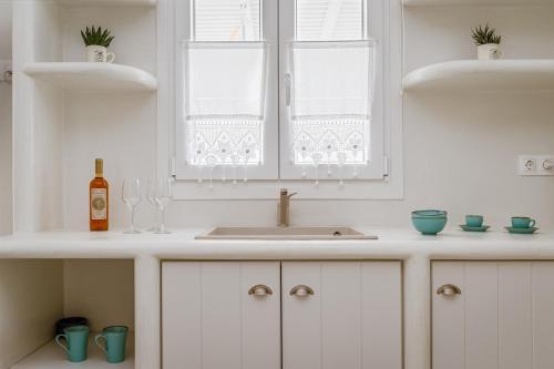 a white kitchen with a sink and two windows at Aeolos Villa Erato in Agkidia