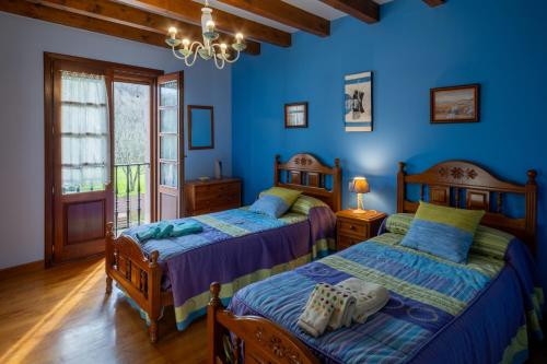 two beds in a bedroom with blue walls at Matxingonea 2 in Urdax