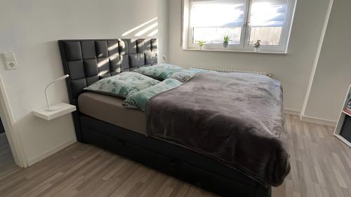 a bedroom with a bed with a black headboard at Petit Bijou in March