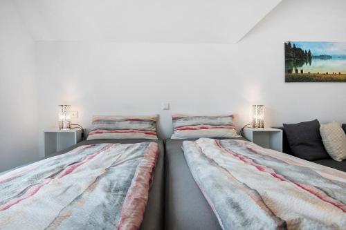 two beds in a white room with two lamps at Appartement Mia in Ihrlerstein