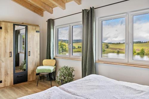 a bedroom with windows and a bed and a chair at Urlaub im Garten Gottes in Klosterlangheim