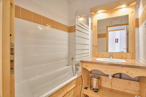 a bathroom with a tub and a sink and a mirror at Les Airelles in Chamrousse