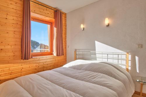 a bedroom with a white bed in a room with a window at Les Airelles in Chamrousse