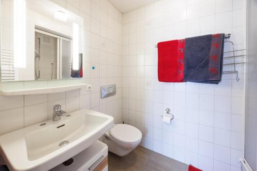 a white bathroom with a toilet and a sink at Gästehaus Wolfgang Weitsee in Ruhpolding