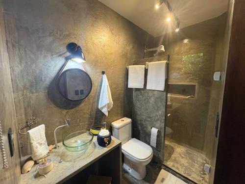a bathroom with a sink and a toilet and a mirror at Rancho Capilé Suítes à Beira Mar in Japaratinga