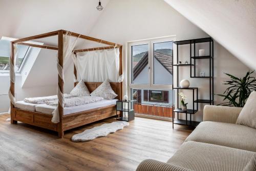 a bedroom with a canopy bed and a couch at Fewo Ebringen Weinbergblick in Ebringen