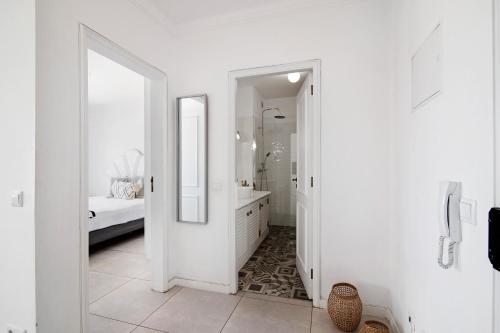 a white bathroom with a tub and a mirror at Lindo T2 com vista mar in Quarteira