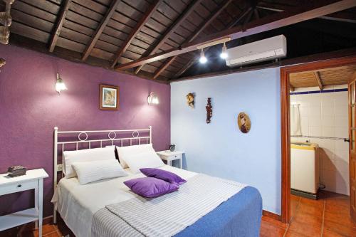 a bedroom with a bed with purple pillows on it at La Chirlaca in Tijarafe