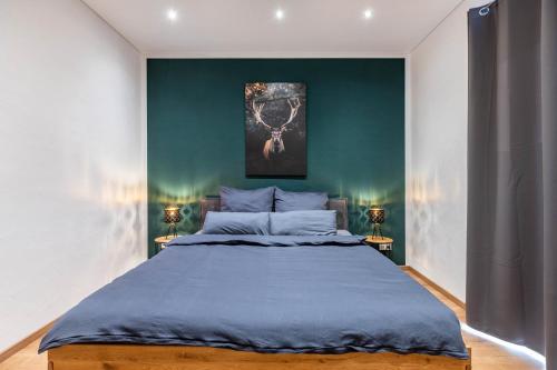 a bedroom with a large bed with a green wall at Ferienhaus Lencer in Ühlingen-Birkendorf