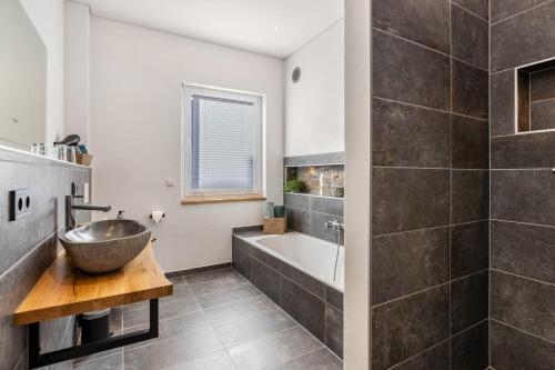 a bathroom with a sink and a bath tub at Ferienhaus Lencer in Ühlingen-Birkendorf