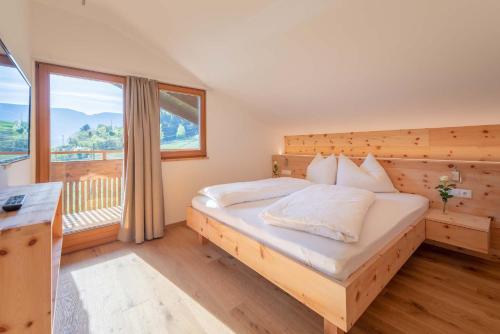 a bedroom with a bed and a large window at Moosbichlerhof in Marlengo