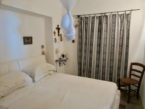 a bedroom with a white bed and a chair at Antico Dammuso Invernale in Pantelleria