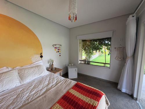 a bedroom with a large bed and a window at Rancho Capilé Suítes à Beira Mar in Japaratinga