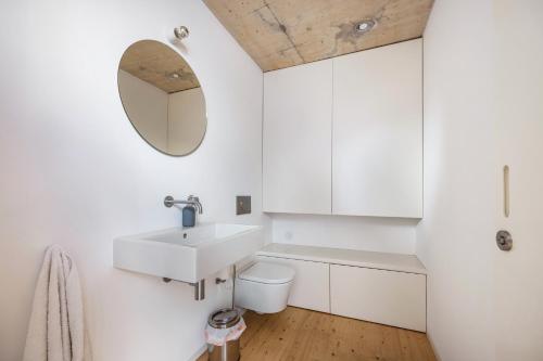 a white bathroom with a sink and a mirror at Olinda House in Odeceixe