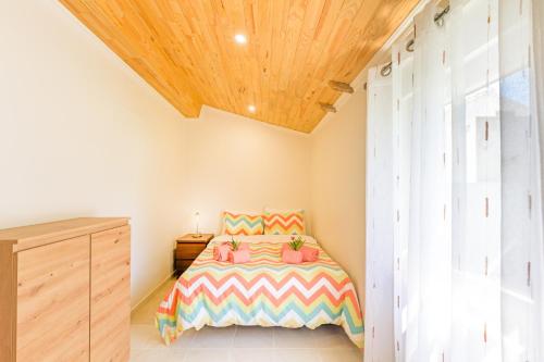 a bedroom with a bed and a wooden ceiling at Casa Dos Lírios in São Teotónio
