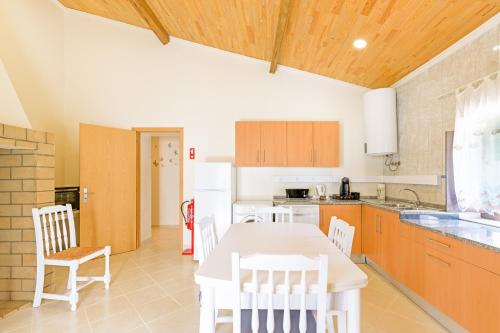 a kitchen with a table and chairs in a room at Casa Dos Lírios in São Teotónio