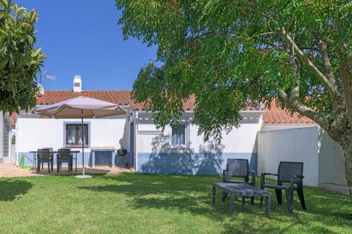 a group of chairs and an umbrella in a yard at Casa Dos Lírios in São Teotónio