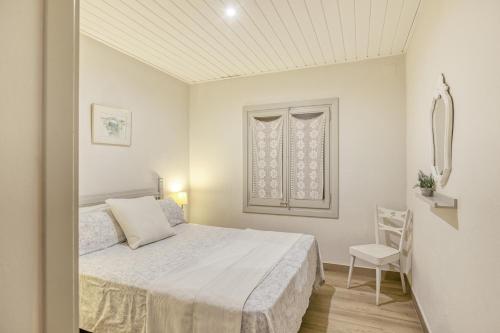 a white bedroom with a bed and a chair at Apartamento Bajo 2 in Begur