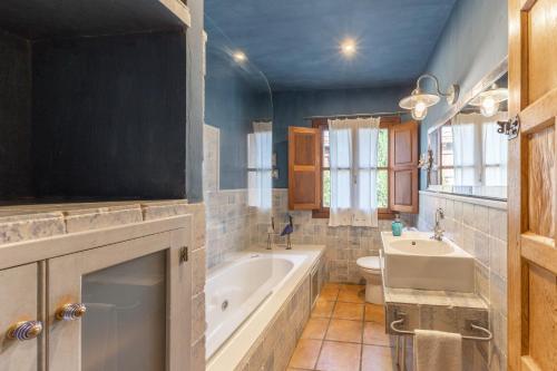 a bathroom with a tub and a toilet and a sink at Dalt La Figuera in La Higuera