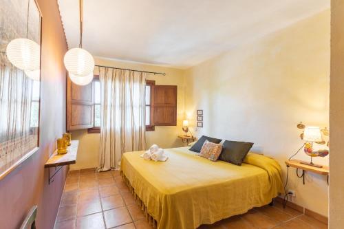 a bedroom with a bed with a yellow bedspread at Dalt La Figuera in La Higuera
