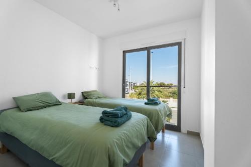 two beds in a room with a window at Casa Bos Palm Tree Villa with Pool in Gran Alacant
