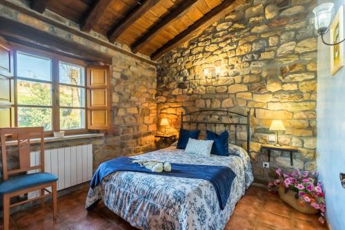 a stone walled bedroom with a bed in a room at Apartamento Juntana 2 in Villacarriedo