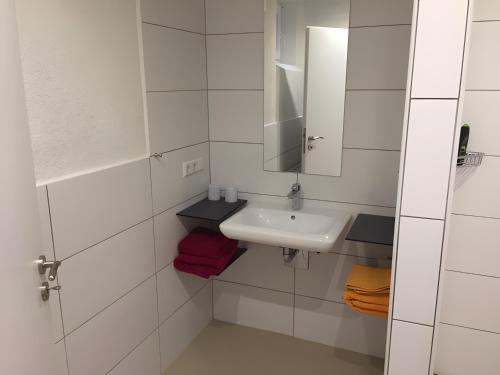 a white bathroom with a sink and a mirror at Ferienwohnung Schwahn in Kleinschönach