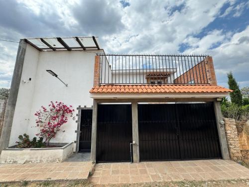 a white building with two garage doors and a balcony at Casa Bella Vizcaína in Mineral de Pozos