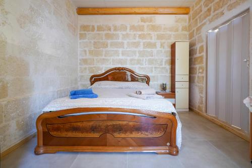 a bedroom with a wooden bed and a brick wall at La Casa di Marta in Faccia di Trippa