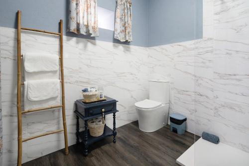 a bathroom with a toilet and a shelf with towels at Pico Boutique House in Lajes do Pico