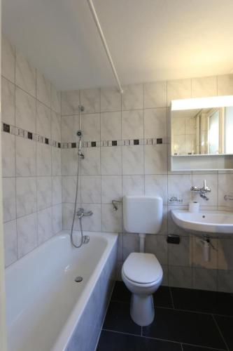 a bathroom with a toilet and a tub and a sink at Apartment Bünda in Davos