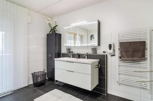 a white bathroom with a sink and a mirror at Turmalin in Überlingen
