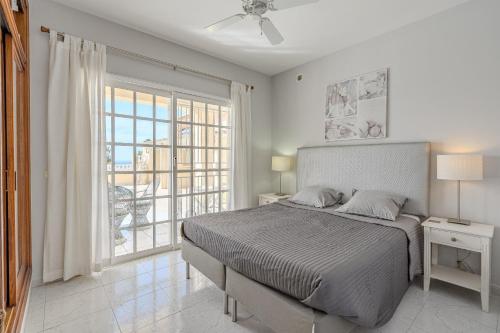 a white bedroom with a bed and a large window at Villa el Yuka , heated pool in Callao Salvaje