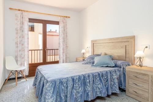 a bedroom with a bed with blue sheets and a window at Can Lopits in L'Escala