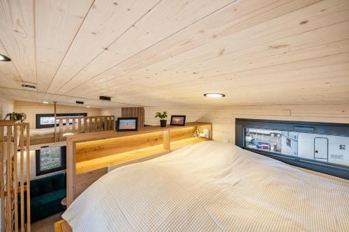 ein großes Bett in einem Zimmer mit Holzdecke in der Unterkunft Tiny House Ingo John 'Shadow' in Sandstedt