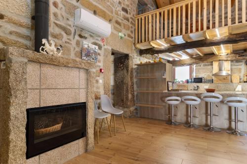 a living room with a fireplace and some stools at Country House - Casa Da Marquinhas in Lama de Ouriço