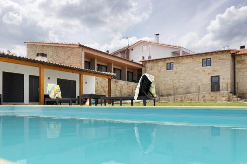 a swimming pool in front of a house at Country House - Casa Da Marquinhas in Lama de Ouriço