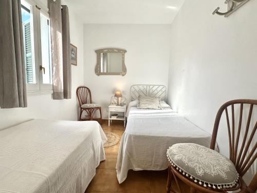 two beds in a room with two chairs and a window at White Sands 3.07 in Arenal d'en Castell